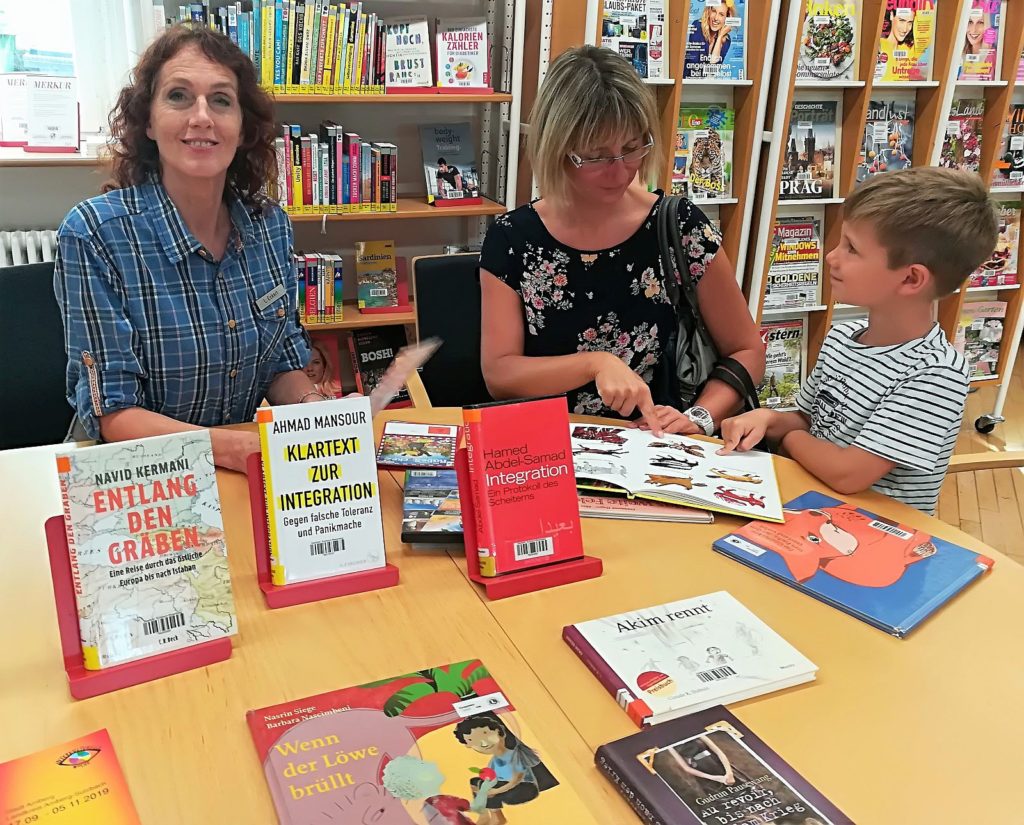 Bibliotheksleiterin Luise Eckert mit dem interessierten Lukas und seiner Mama beim Schmökern.