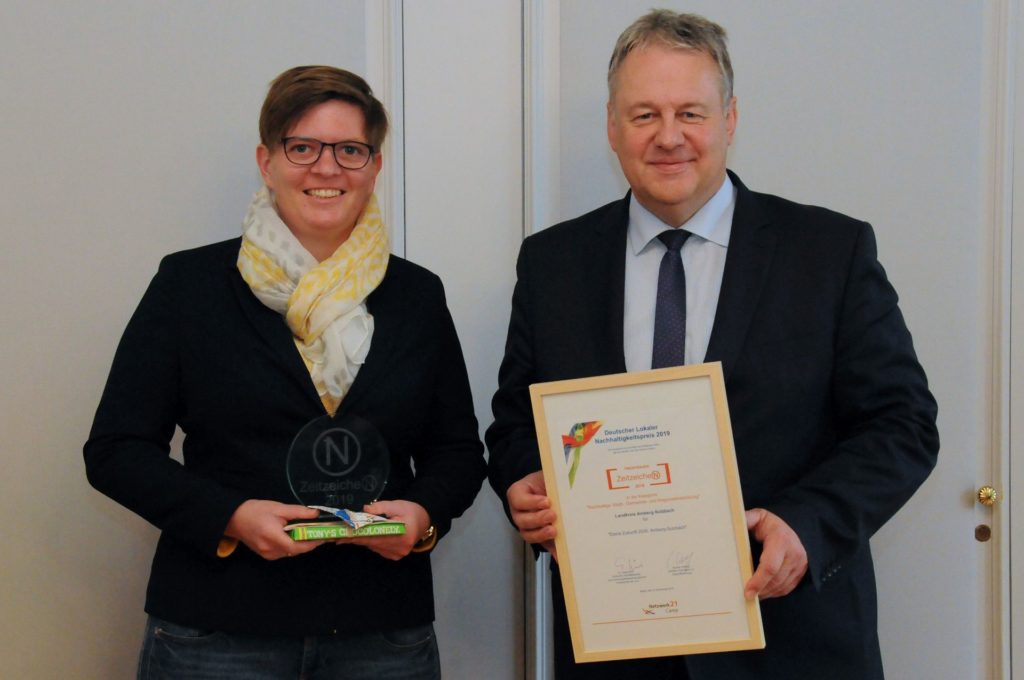 Landrat Richard Reisinger und Regionalmanagerin Maria Regensburger präsentieren stolz die Trophäe, den Nachhaltigkeitspreis ZeitzeicheN, und die Urkunde. Foto: Christine Hollederer