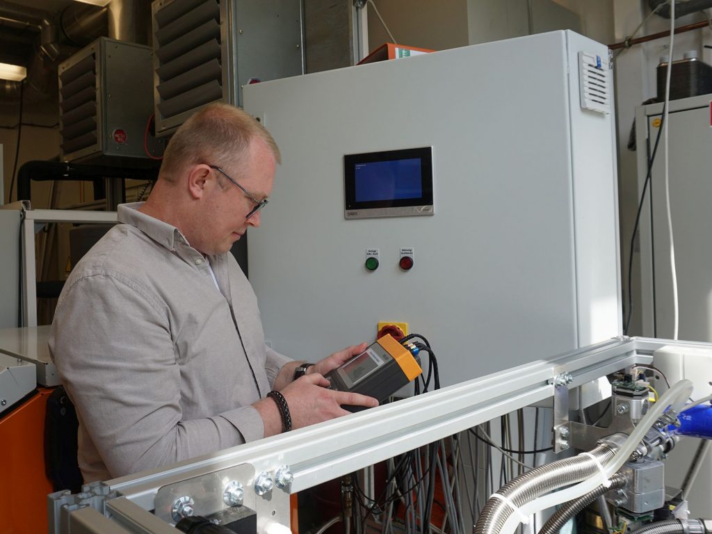 Doktorand Jegor Kern bei der Arbeit am intelligenten Mikro-Blockheizkraftwerk im Verfahrenstechnik-Labor der OTH in Weiden  Foto: Misch/OTH Amberg-Weiden