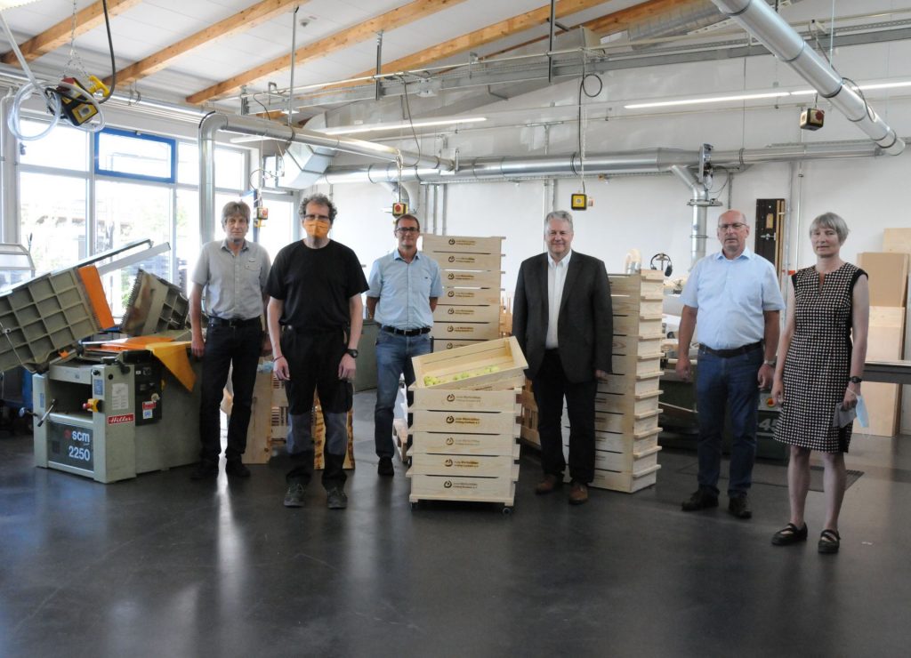 In der Schreinerei der Jura Werkstätten präsentierten Werner Prüll (Technischer Leiter), Mitarbeiter Hubert Scheffmann, Geschäftsführer Bernhard Albrecht, Landrat Richard Reisinger, Eduard Freisinger (Vorsitzender Jura Werkstätten Amberg-Sulzbach e.V.) und Ökomodellregion-Projektmanagerin Barbara Ströll (v.li.) die regionalen Holzkisten für Obst. Die können ab sofort bei den Jura Werkstätten gekauft werden. Foto: Christine Hollederer