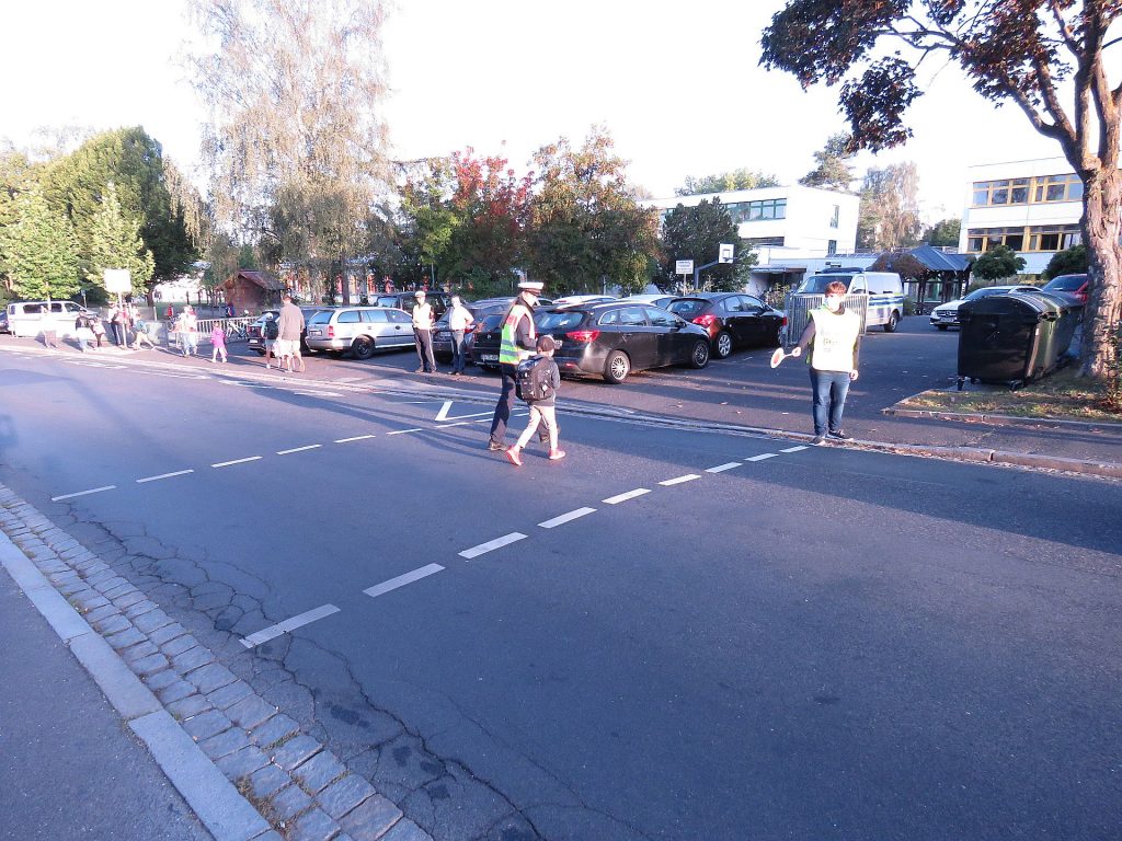 PM Anwìn Selina Dirrigl unterstützt einen Abc-Schützen mit Hilfe eines Schülerlotsens beim sicheren Überqueren der Fahrbahn vor der Willmannschule Foto: Polizei Amberg