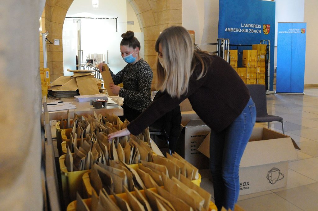 Anna-Lena Hörl und Julia Christl (v.li.) sind zwei der fleißigen Helfer im Landratsamt, die derzeit Masken und Anschreiben in Kuverts verpacken und die Briefe an besonders bedürftige Menschen im Landkreis Amberg verschicken. Foto: Christine Hollederer