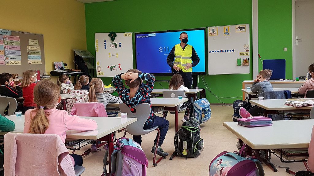 Foto: Im Theorieteil erklärt und zeigt POK Markus Neumeyer im Klassenzimmer die Wichtigkeit und Wirkungsweise von reflektierenden Westen. 