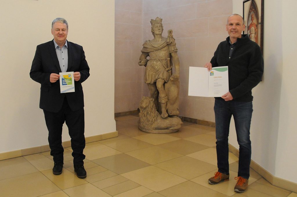 Im Rahmen der Bauausschusssitzung überreichte Landrat Richard Reisinger an Kreisrat Christian Steger, dem Firmeninhaber von Holzbau Steger, die Urkunde für den Umwelt- und Klimapakt Bayern Foto: Christine Hollederer