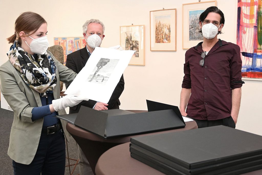 Die Leiterin von Stadtmuseum und Stadtgalerie Julia Riß, Kulturreferent Dr. Fabian Kern und der Vorsitzende des A.K.T. Kunstvereins Marcus Trepesch bei der Vorstellung der Sammelmappe "Covidium" mit zehn Druckgrafiken zum Thema Corona Foto: Susanne Schwab, Stadt Amberg