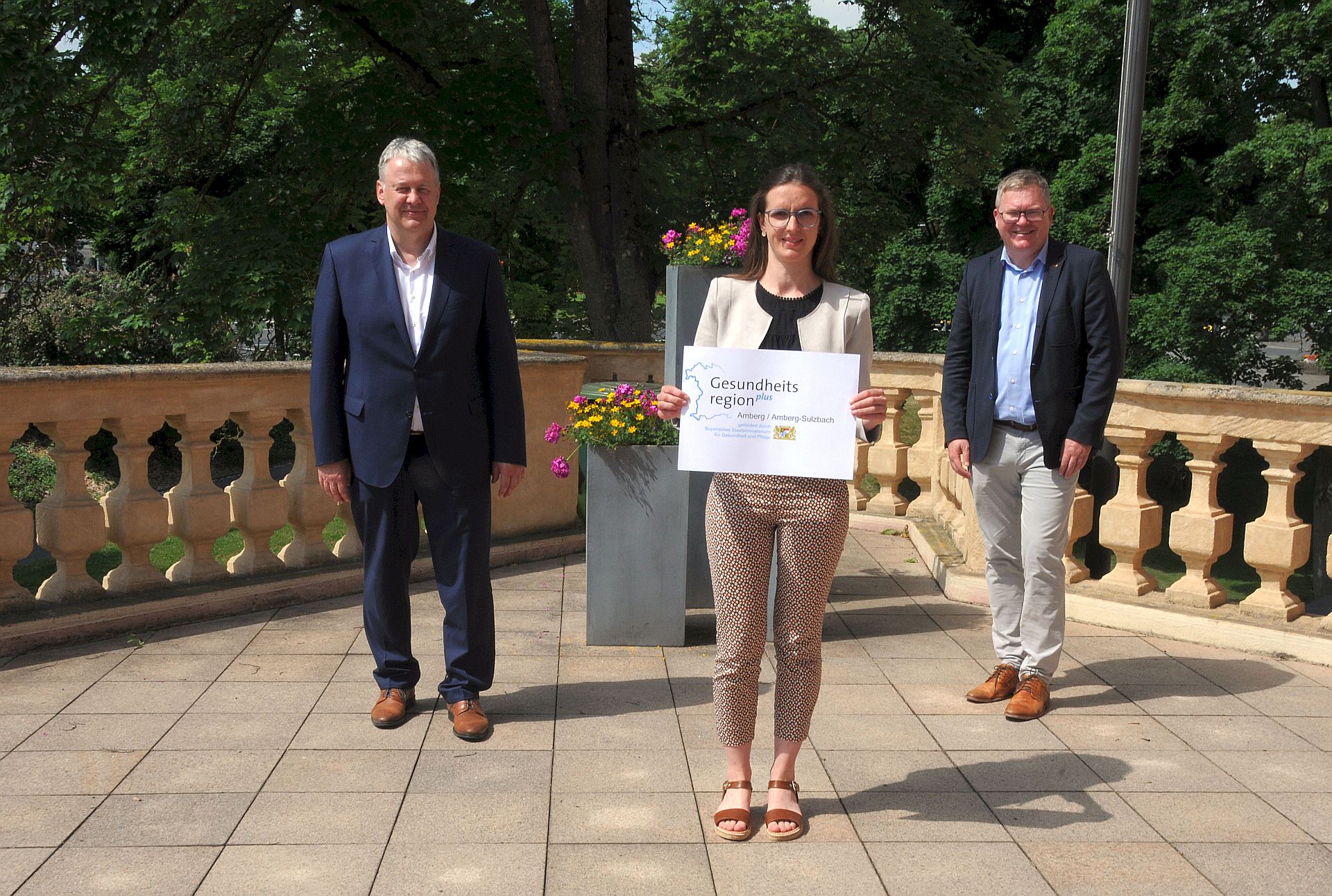 Foto: Christine Hollederer Landrat Richard Reisinger und Oberbürgermeister Michael Cerny unterzeichneten den Ergänzungsvertrag zur Namensänderung (v. l.). Die gemeinsame Gesundheitsregionplus nennt sich ab sofort „Gesundheitsregionplus Amberg/Amberg-Sulzbach“, wie das Logo zeigt, das Geschäftsstellenleiterin Christine Hecht präsentiert.