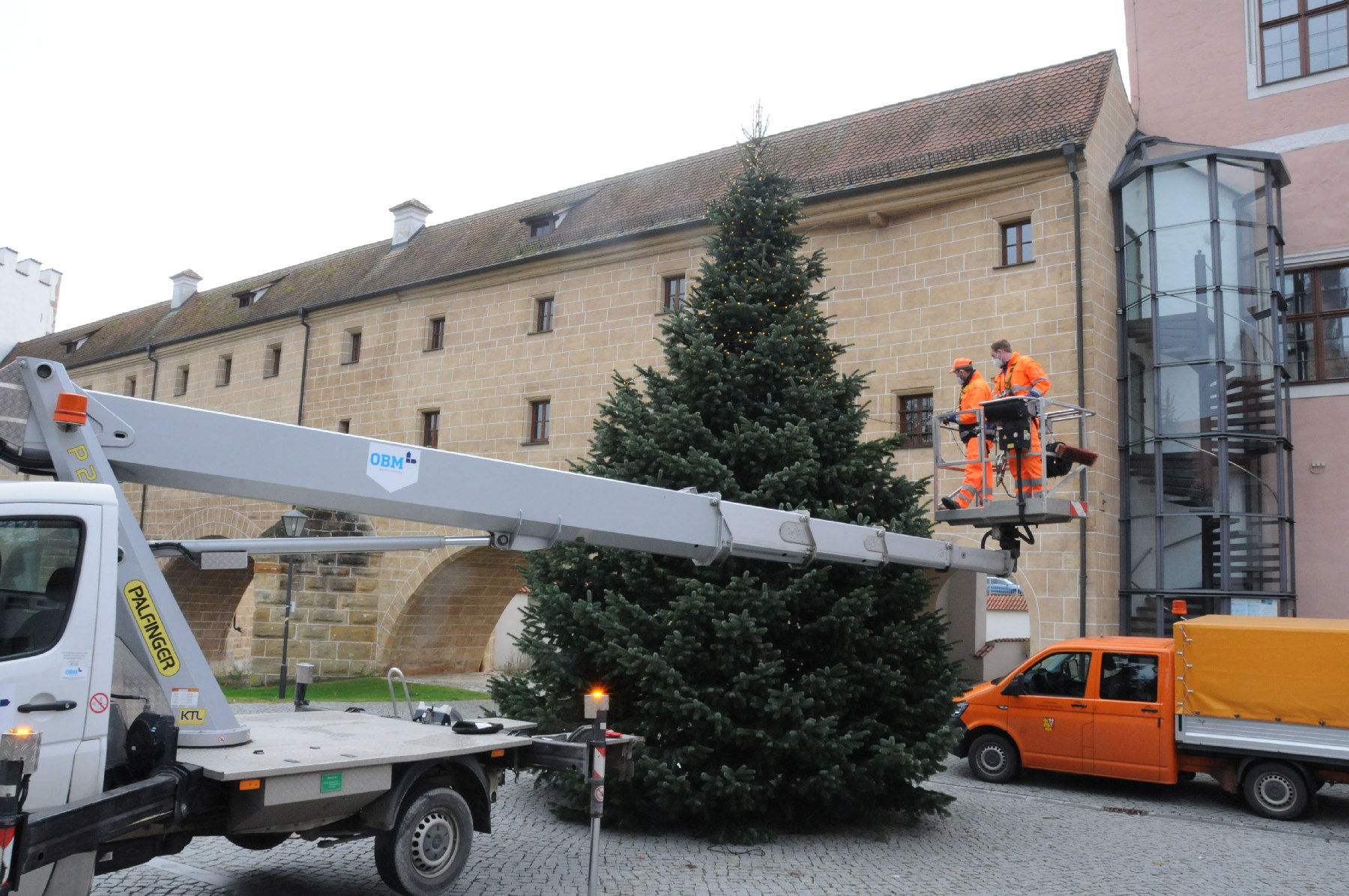 Zwei Mitarbeiter des Bauhofs haben den Weihnachtsbaum im Innenhof mit Lichterketten geschmückt. Bis vor kurzem stand der Baum noch in Köfering Foto: Christine Hollederer