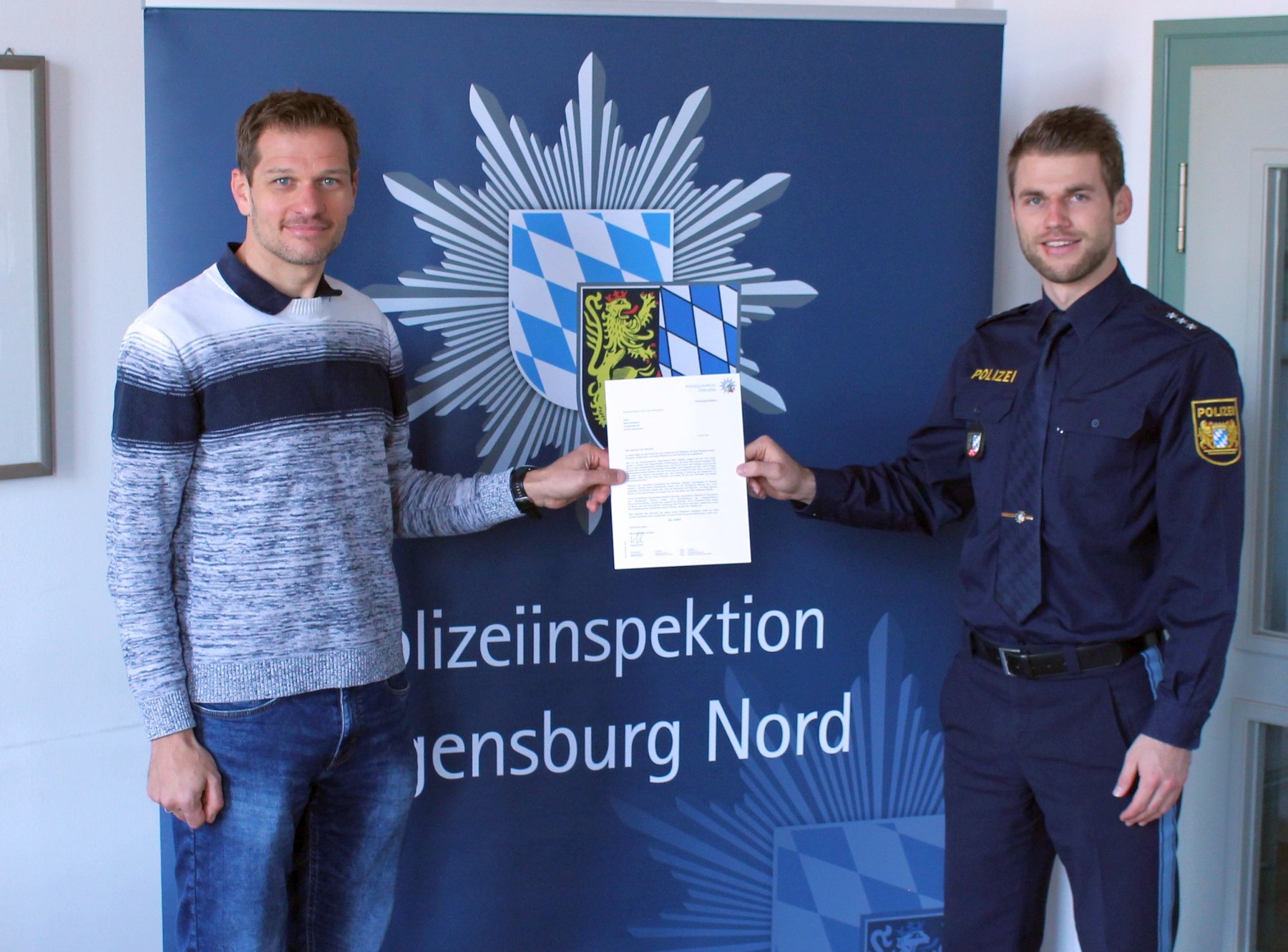 Matthias Gröger, Polizeihauptkommissar (rechts, Dienststellenleiter der PI Regensburg Nord) bei der Übergabe des Dankesschreibens und der Geldzuwendung an Herrn Marco Bscheidl (links) Quelle: PI Regensburg Nord