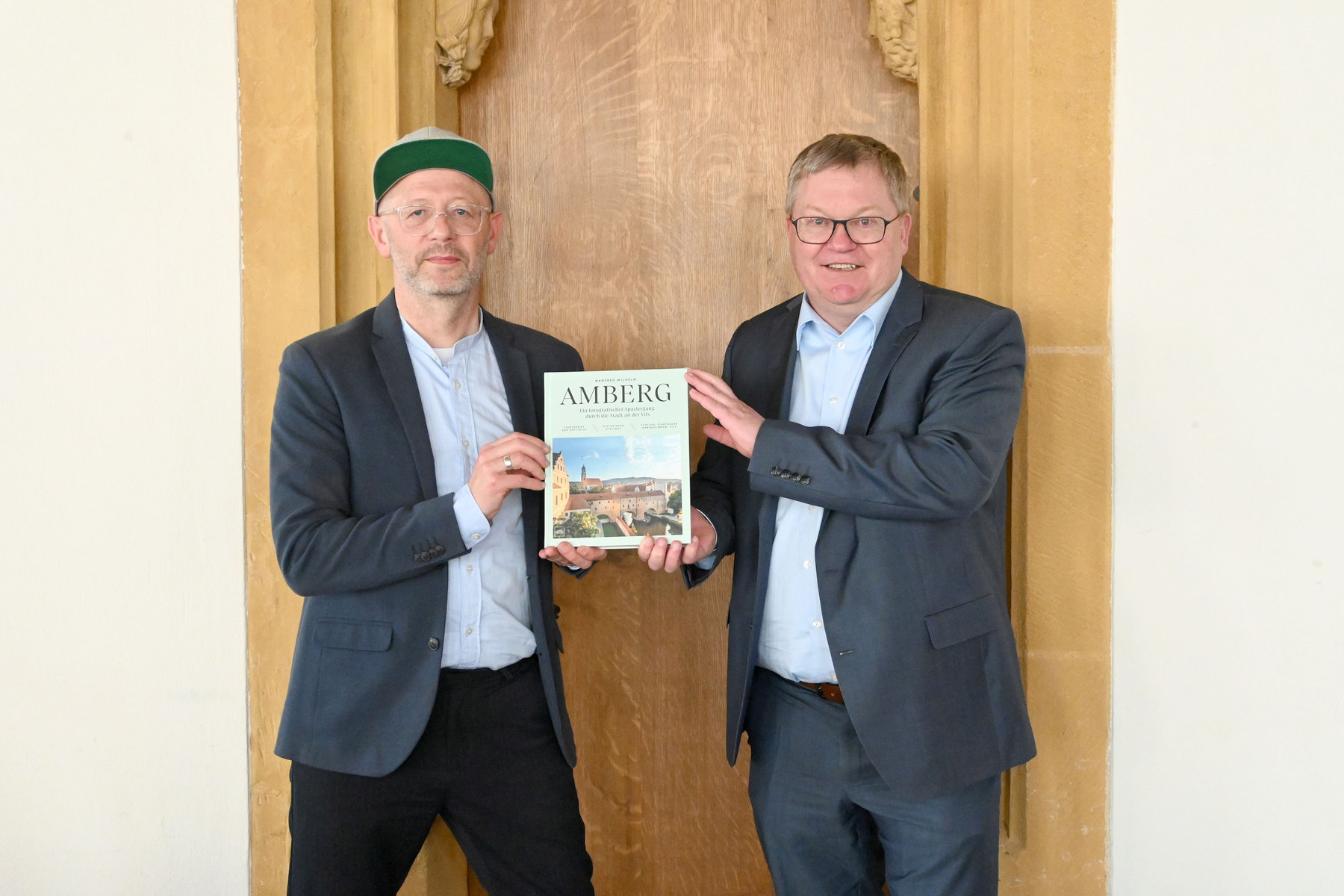 Fotograf Manfred Wilhelm (links) überreicht OB Michael Cerny ein druckfrisches Exemplar seines neuen Bildbandes mit rund 870 Aufnahmen aus der Stadt Amberg Foto: Susanne Schwab, Stadt Amberg